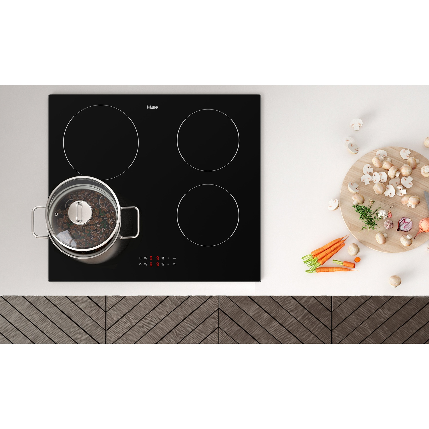 Une plaque à induction noire avec une casserole dessus, à côté de carottes et de champignons.