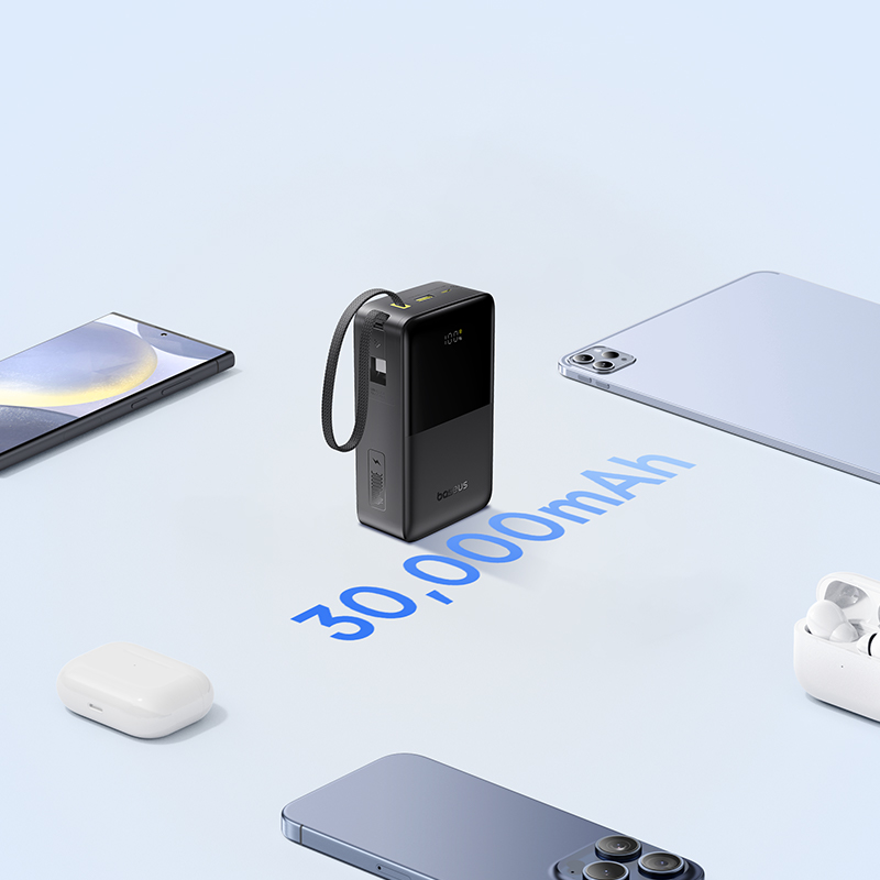 Fekete powerbank zsinórral, okostelefonok, tablet és fülhallgatók mellett.