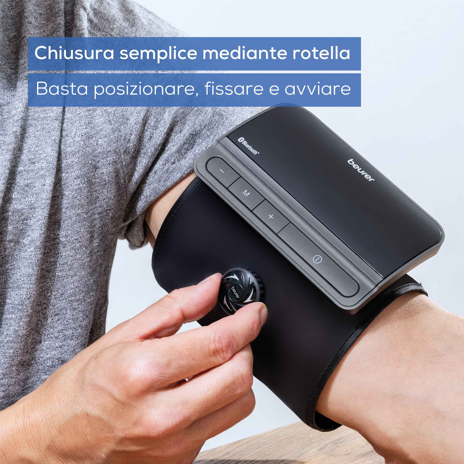 Una mano regola un misuratore di pressione Beurer nero su un braccio.