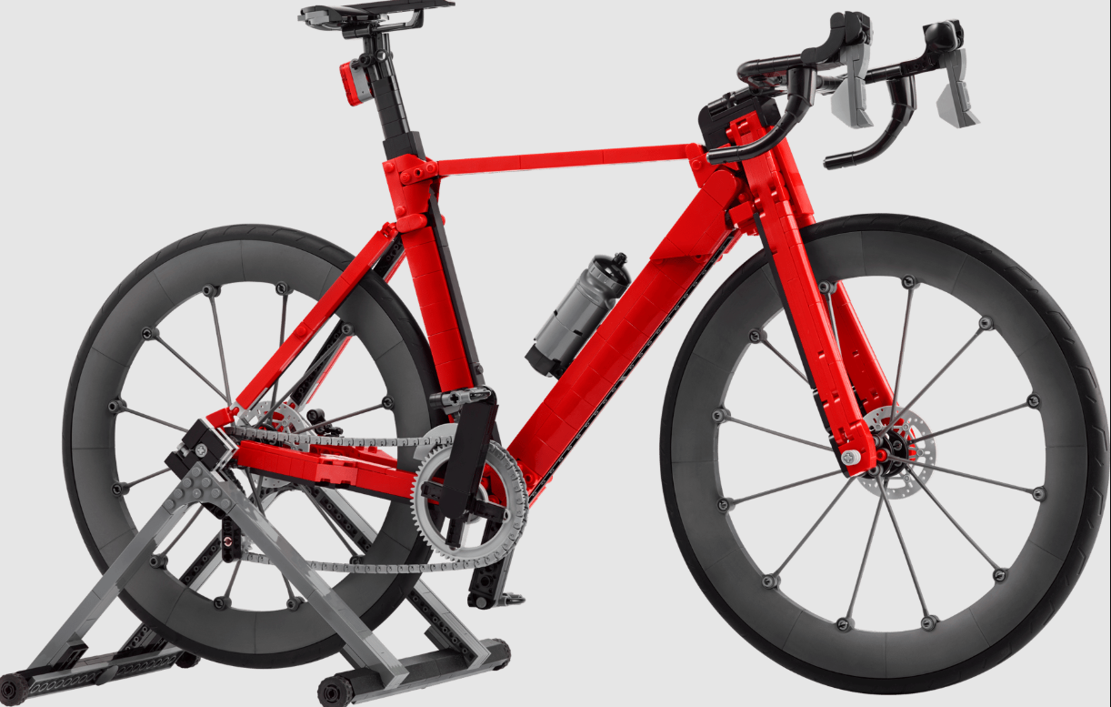 Rotes Lego-Fahrrad auf einem Ständer mit grauen Rädern und schwarzen Lenkern.