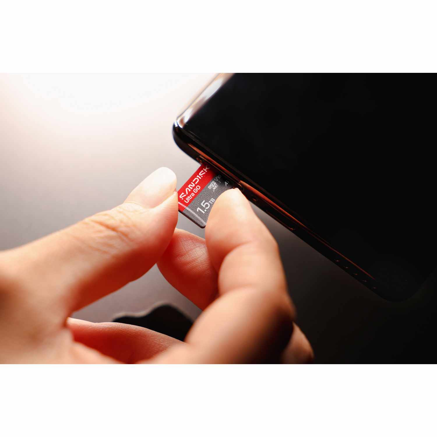 Una mano inserta una tarjeta microSD SanDisk Ultra Go de 1,5 TB en un smartphone.