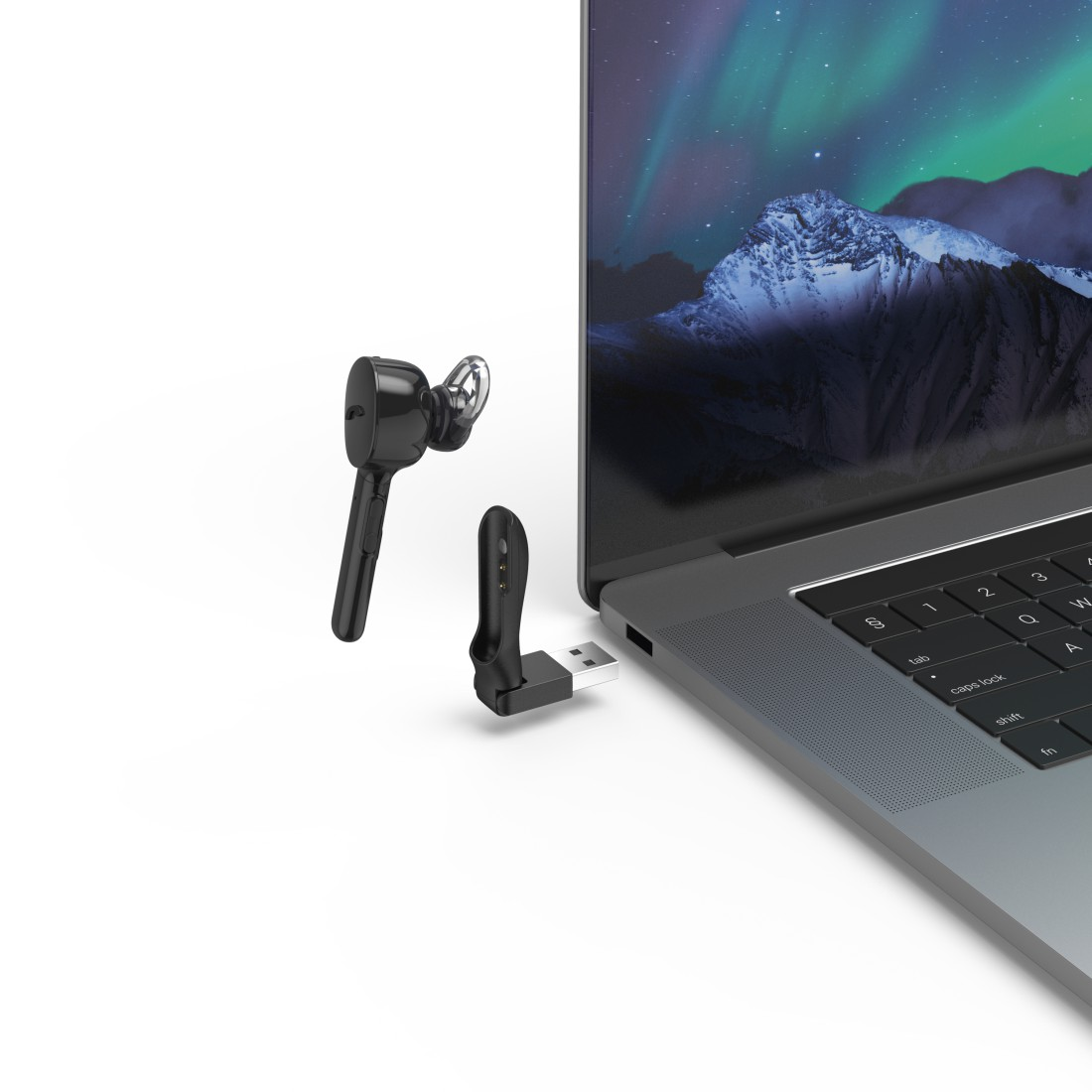 Czarny zestaw słuchawkowy i adapter USB przed laptopem z zorzą polarną na ekranie.