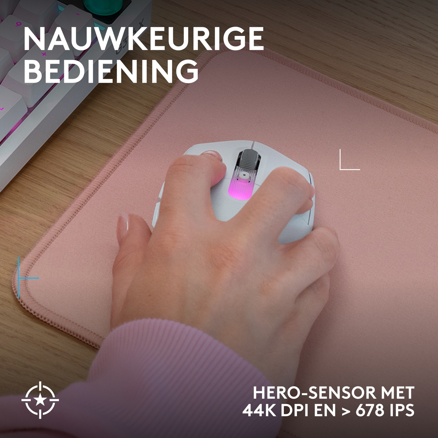 Een hand gebruikt een witte muis op een roze mat naast een toetsenbord.
