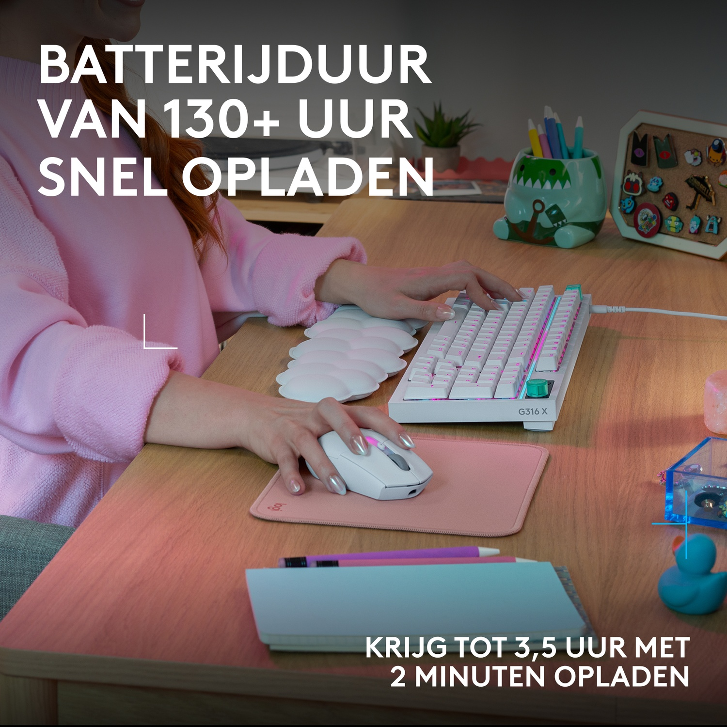 Een persoon typt op een wit toetsenbord, ernaast een witte muis op een roze mat.