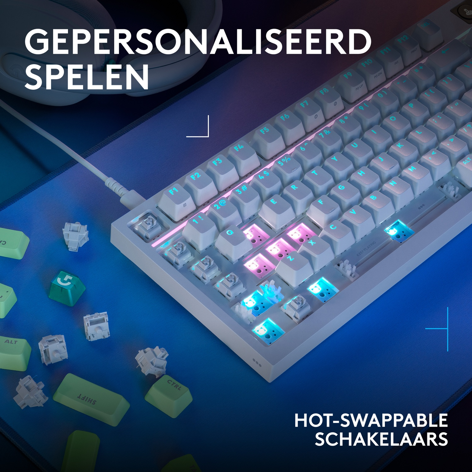 Een wit toetsenbord met RGB-verlichting en losse keycaps op een blauwe mat.