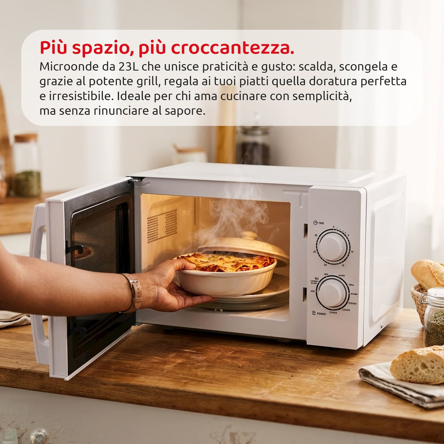 Una mano inserisce una teglia in un microonde bianco aperto, con vapore.