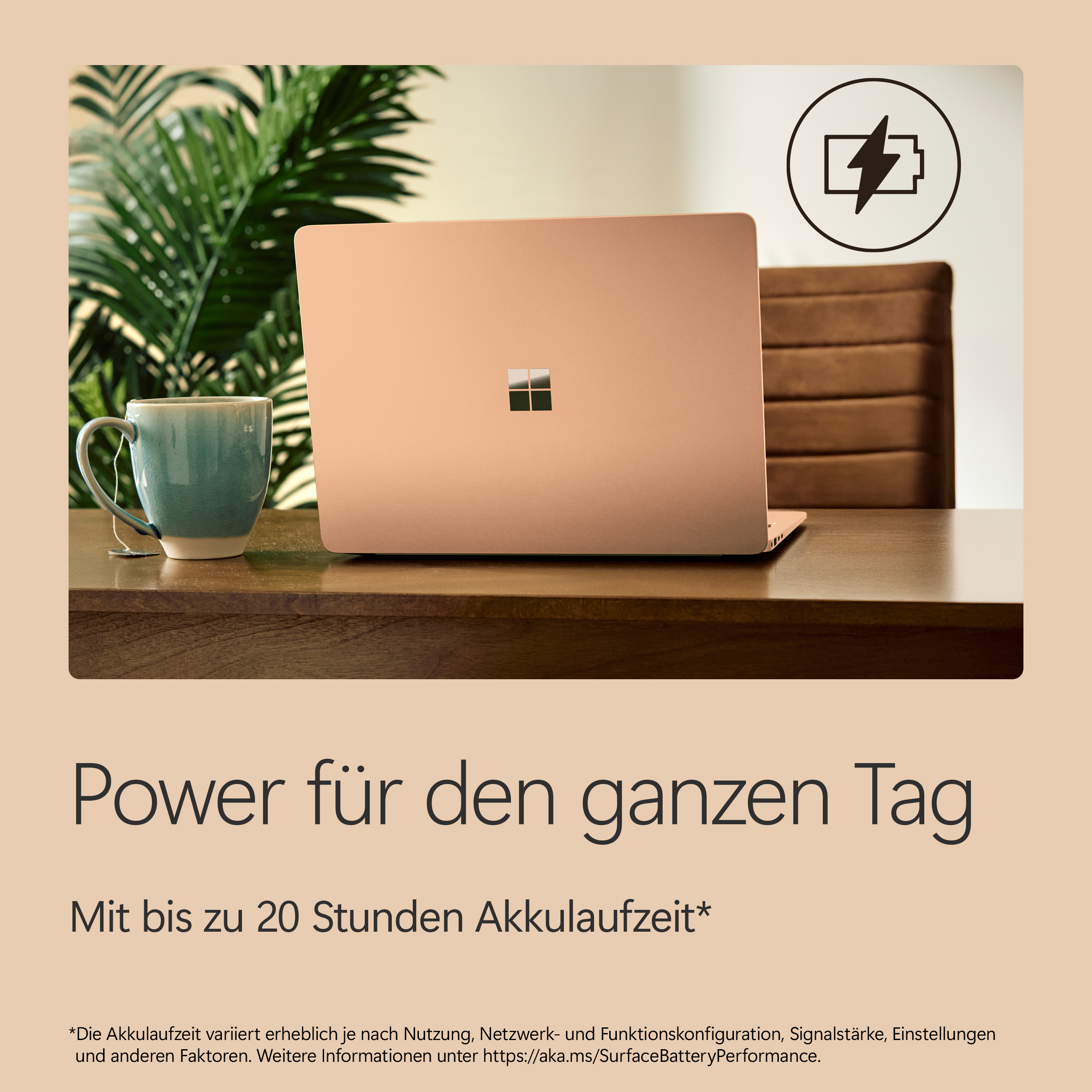 Ein roségoldener Laptop steht auf einem Holztisch neben einer Teetasse und Pflanzen.