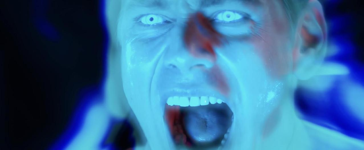 Mann mit leuchtenden Augen schreit, blaues Licht umgibt ihn.