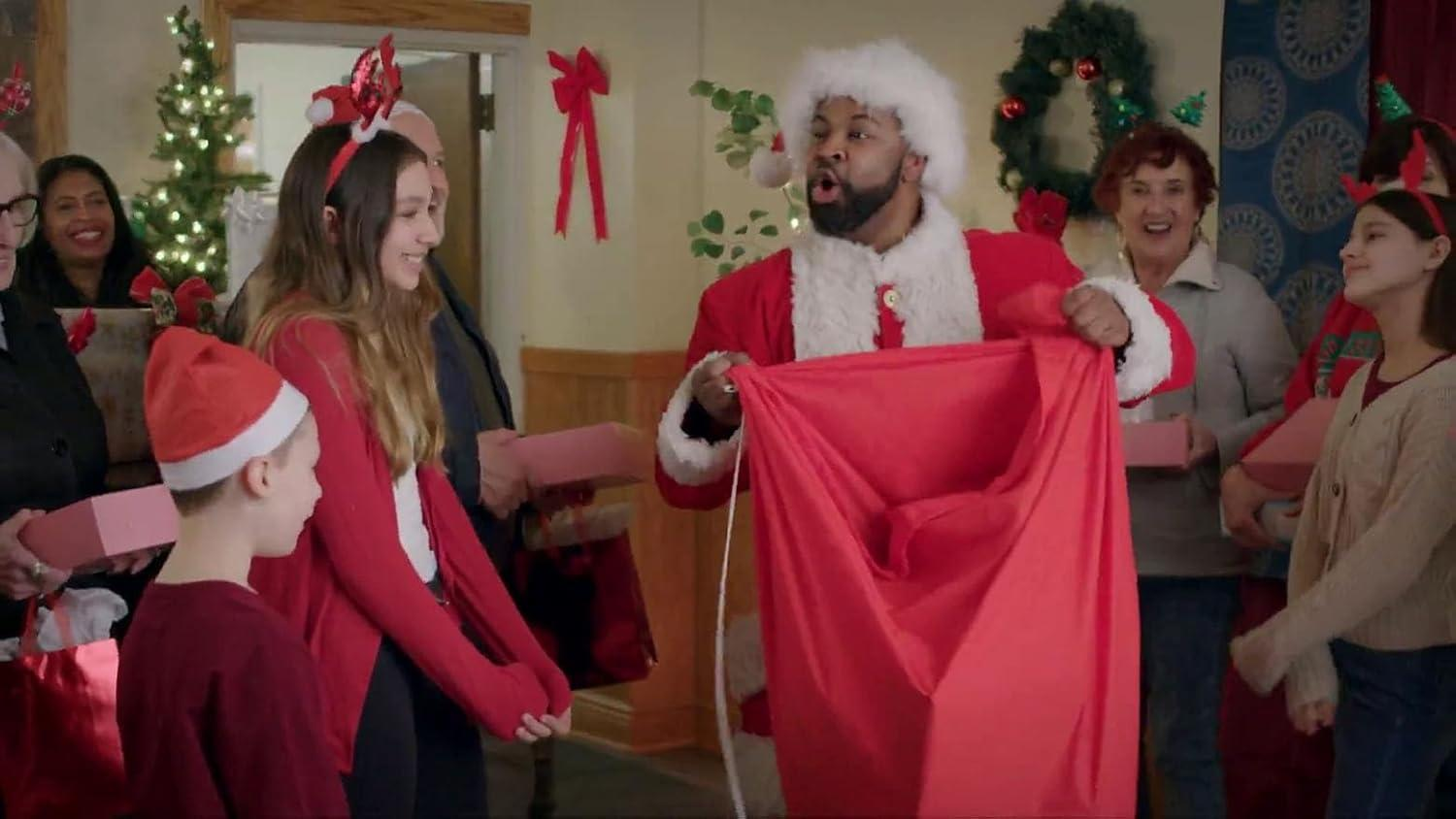 Weihnachtsmann mit großem Sack und Familie mit Geschenken.