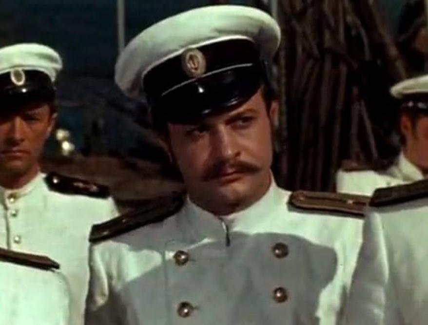 Männer in weißen Uniformen mit Mützen und Schnurrbärten stehen nebeneinander.