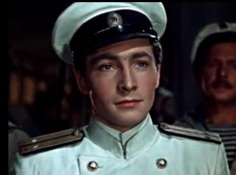 Ein junger Mann in einer hellblauen Marineuniform und weißem Hut blickt nach vorn.