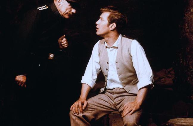 Ein Mann in Uniform spricht mit einem Mann in Weste und Hemd.