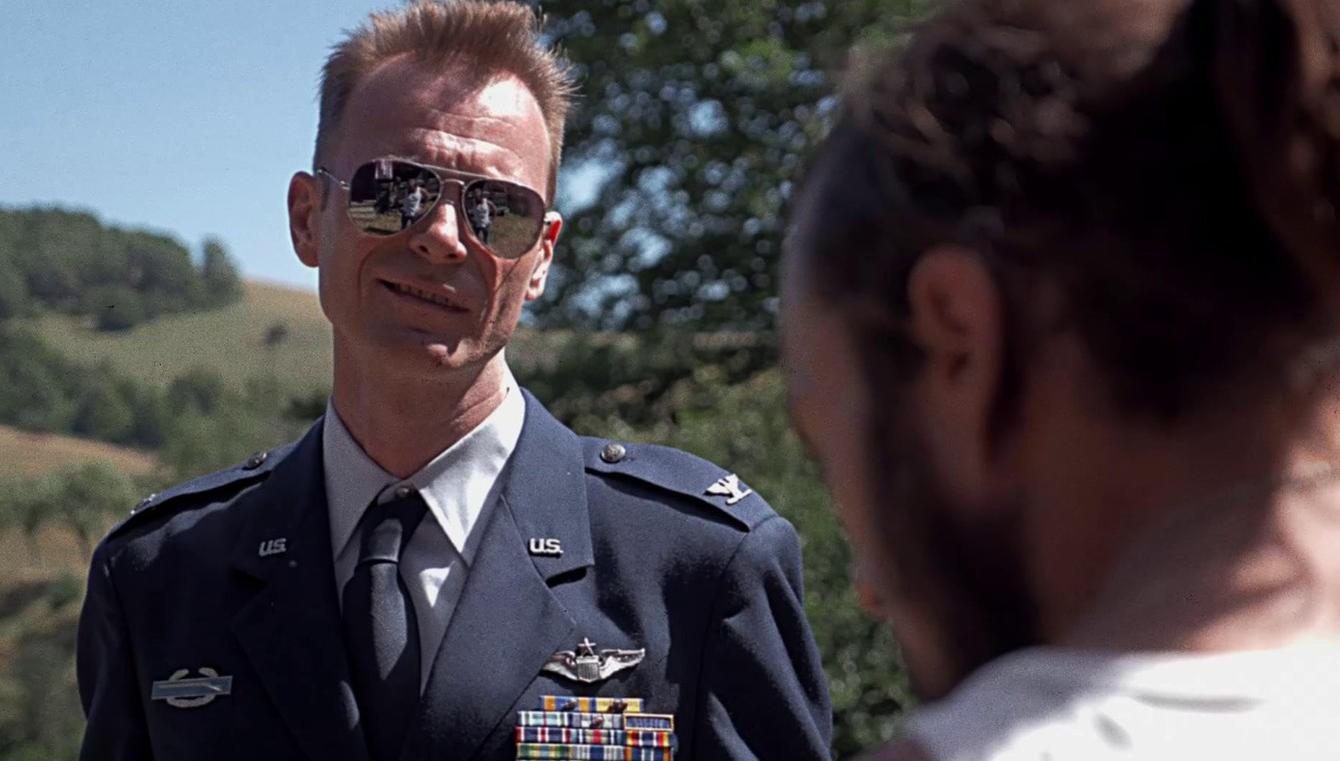 Ein Mann in Uniform mit Sonnenbrille spricht mit jemandem.