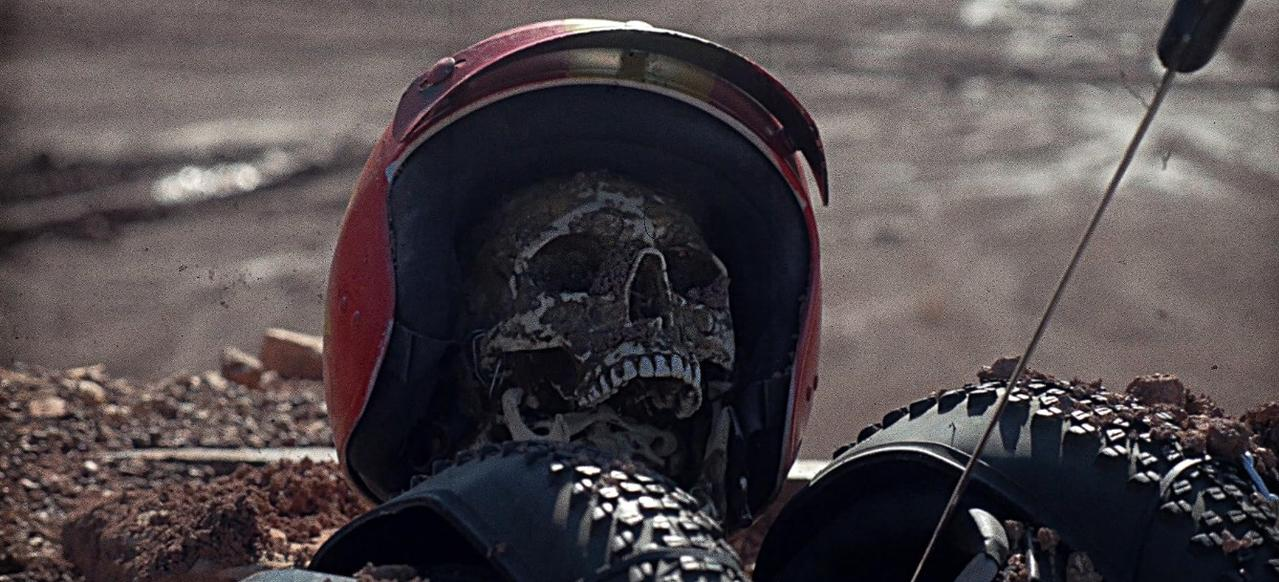 Ein menschliches Skelett in einem roten Helm und Schutzkleidung liegt im Freien.