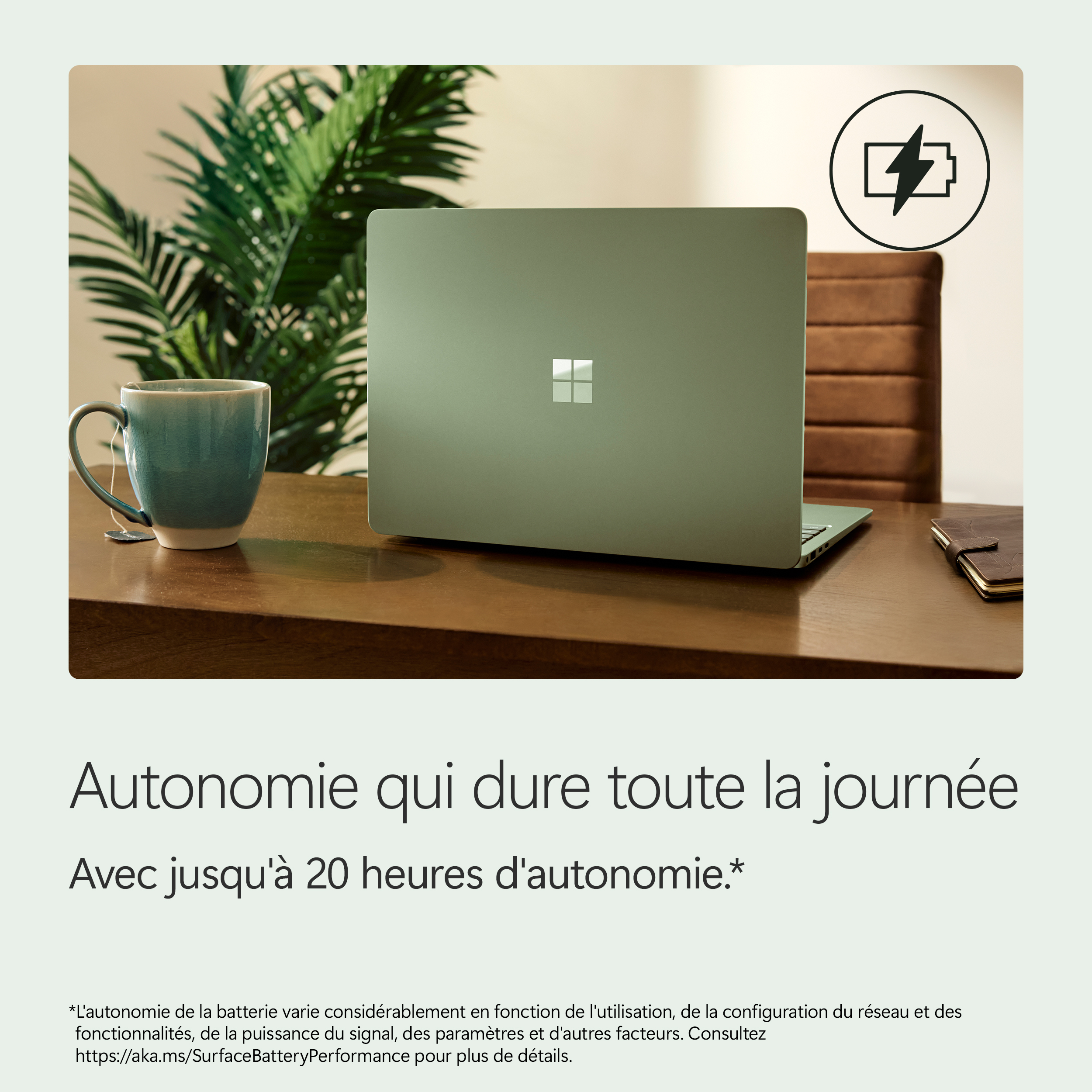 Ordinateur portable vert sur un bureau avec tasse, plante et icône de charge.