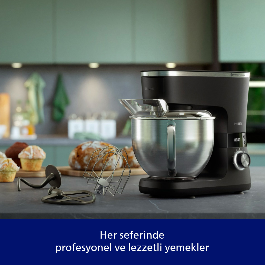 Paslanmaz çelik haznesine sahip siyah stand mikseri, hamur işlerinin yanında tezgahta.