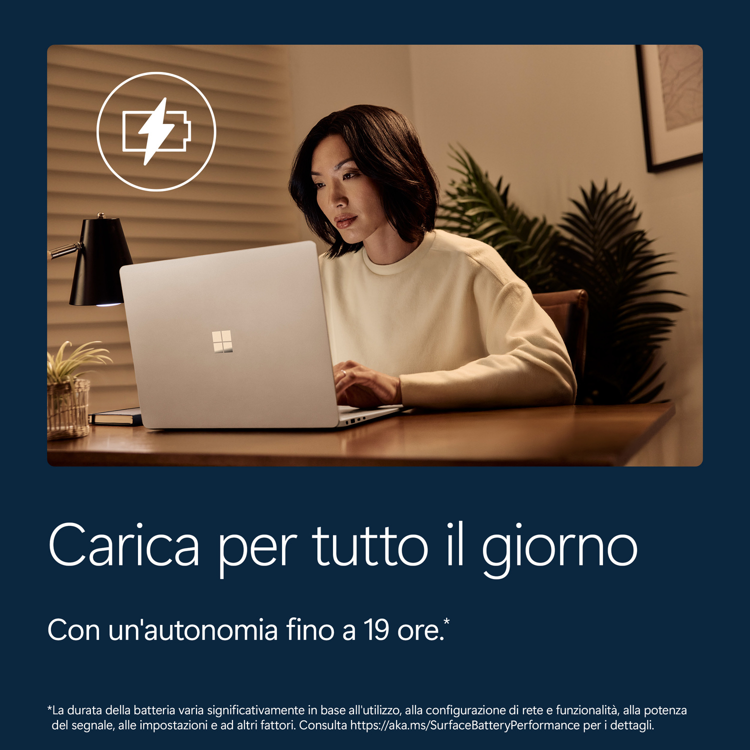 Una donna lavora su un laptop; è visibile un'icona di ricarica.