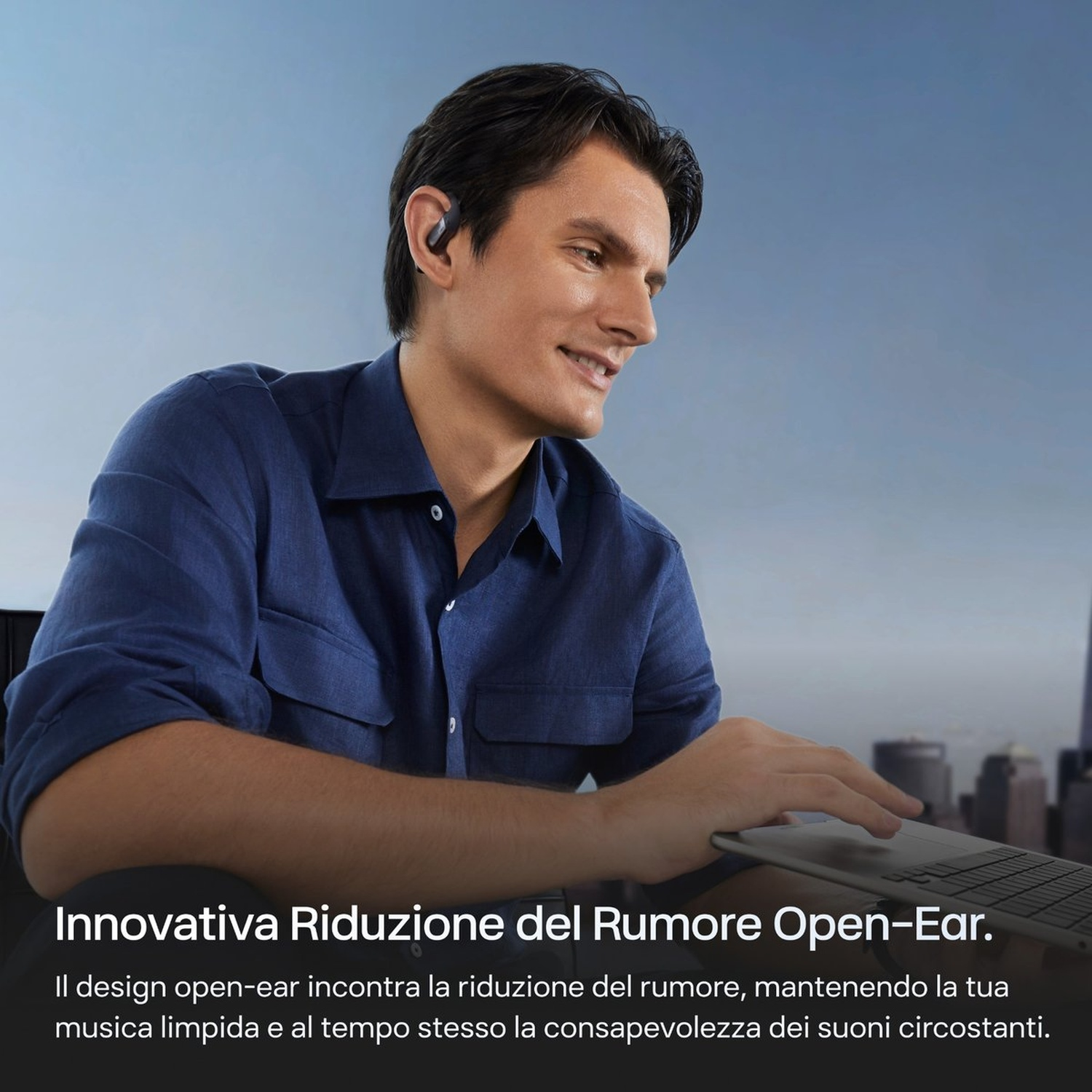 Uomo con auricolari e laptop davanti a skyline cittadino.