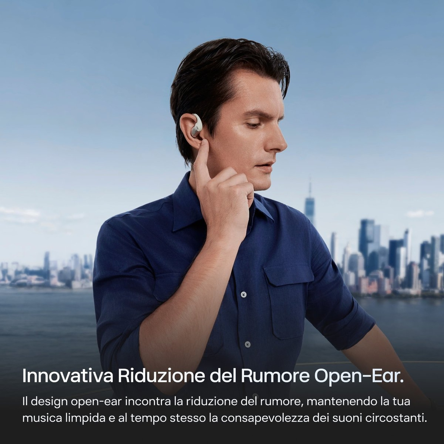 Uomo con auricolari open-ear davanti a uno skyline cittadino.