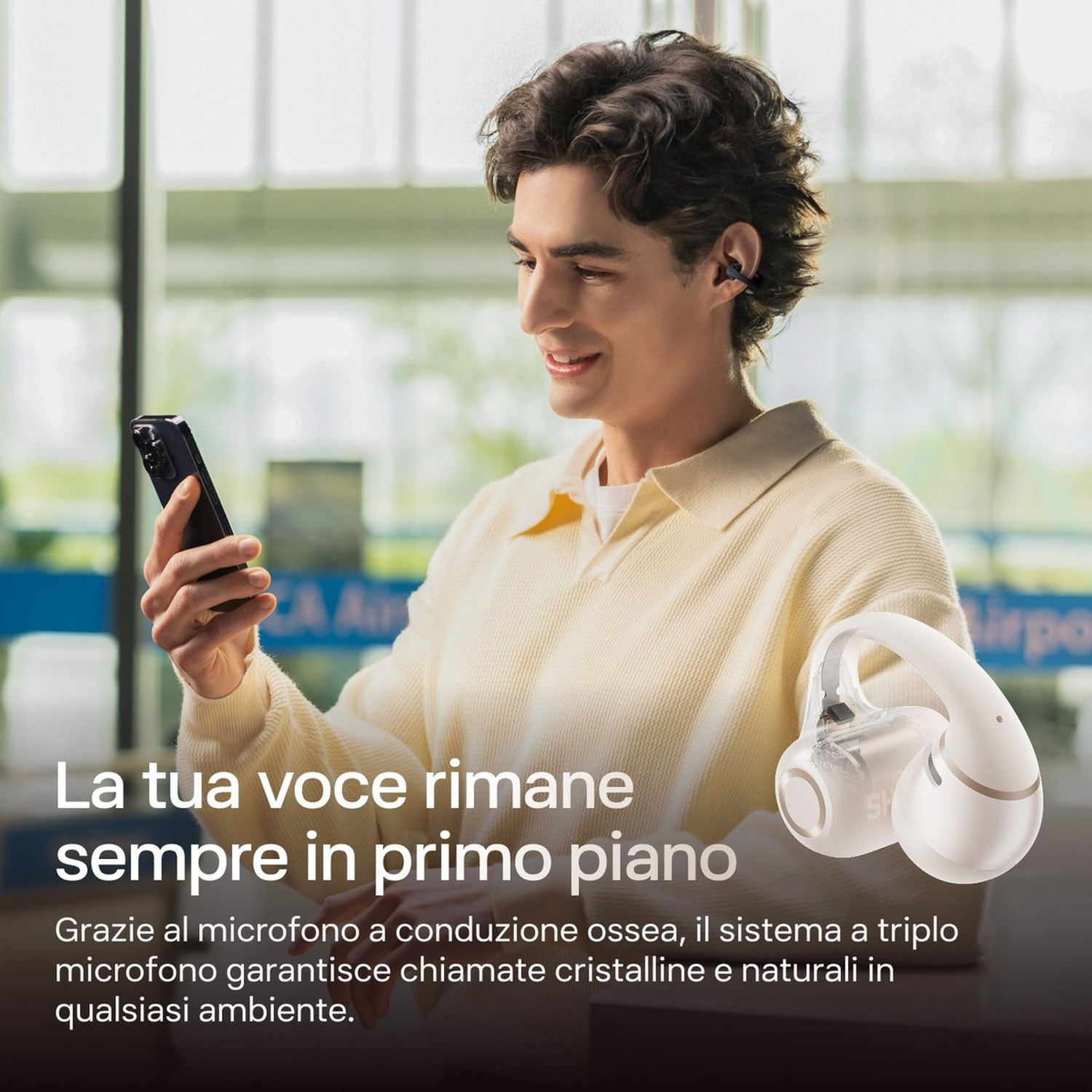 Un uomo tiene uno smartphone e indossa auricolari. Un auricolare bianco è in primo piano.