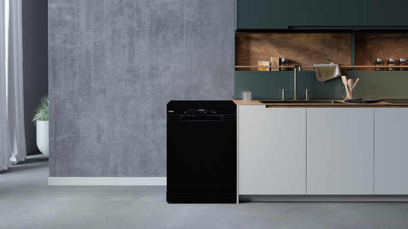 Een zwarte vaatwasser staat in een moderne keuken met een grijze betonnen muur.