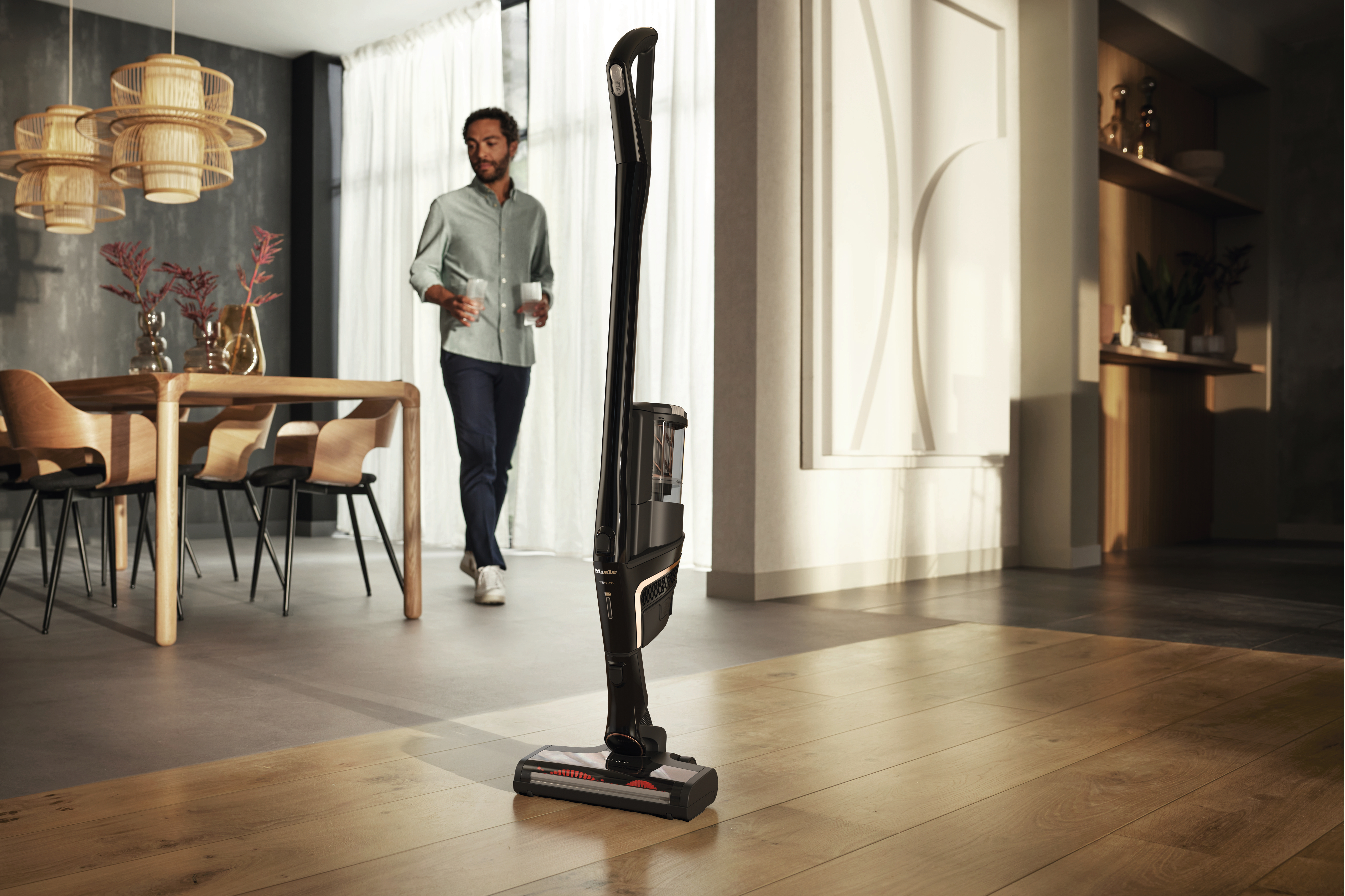 Ein Mann geht an einem Staubsauger vorbei, der in einem modernen Esszimmer steht.