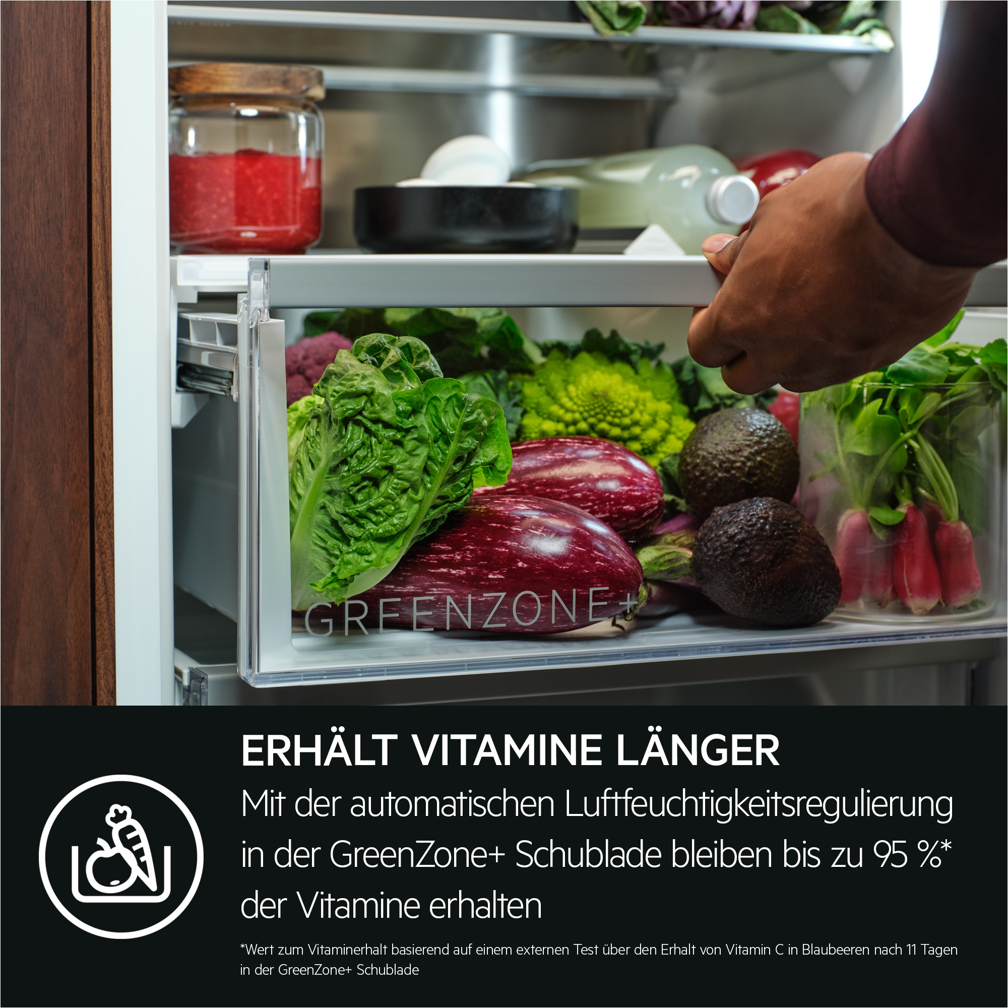 Ein Mann schließt eine Kühlschublade mit Gemüse, darunter Salat, Auberginen und Avocados.