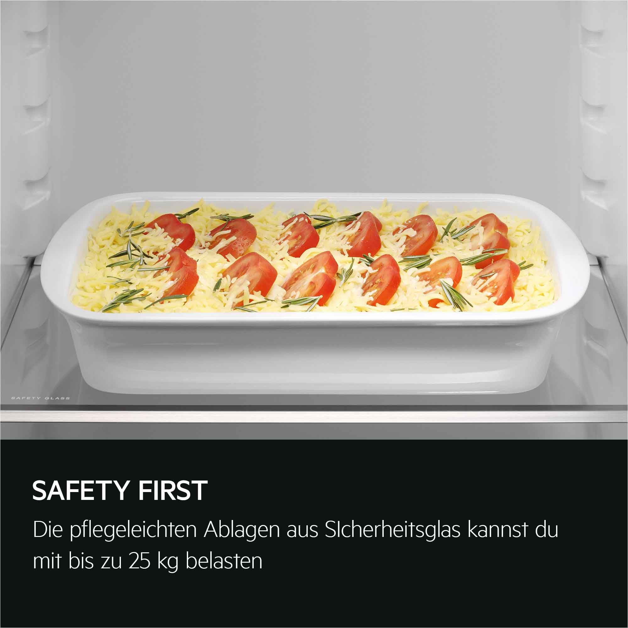 Eine weiße Auflaufform mit geriebenem Käse, Tomaten und Rosmarin auf einem Regal.