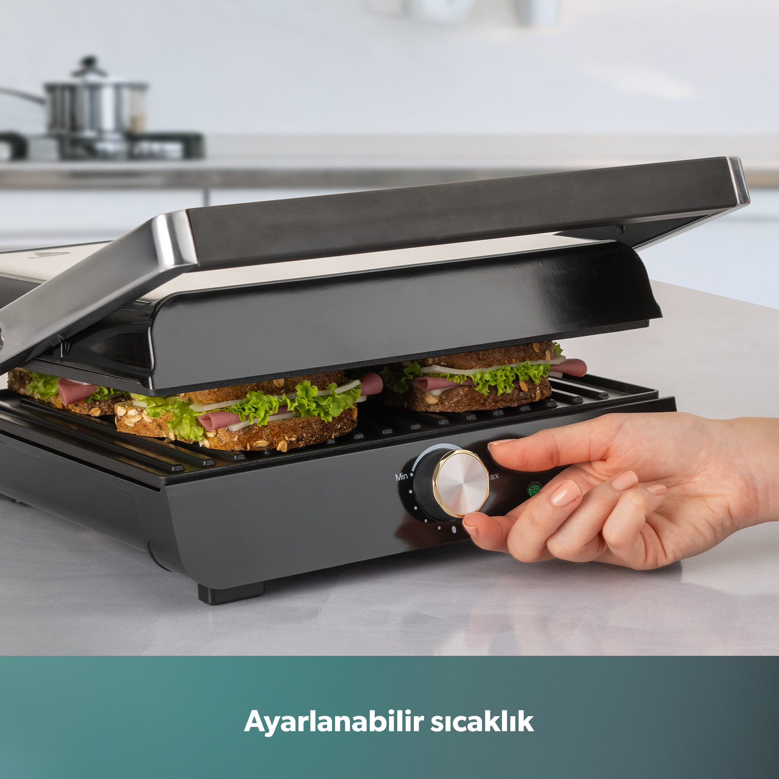 İki sandviçli sandviç makinesi, bir el sıcaklık düğmesini çeviriyor.