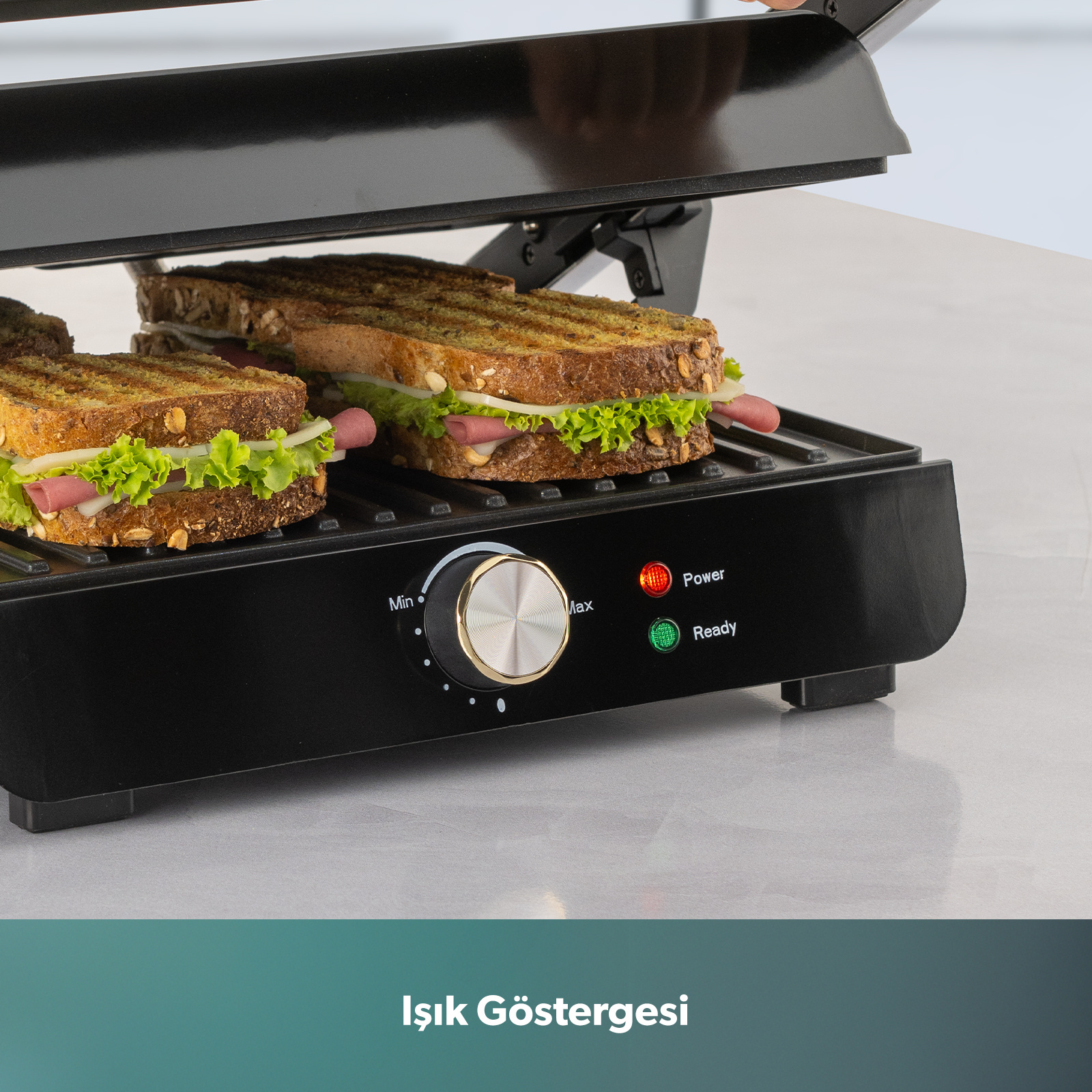Siyah bir tost makinesinde sandviçler hazırlanıyor. Kırmızı ve yeşil gösterge ışıkları yanıyor.
