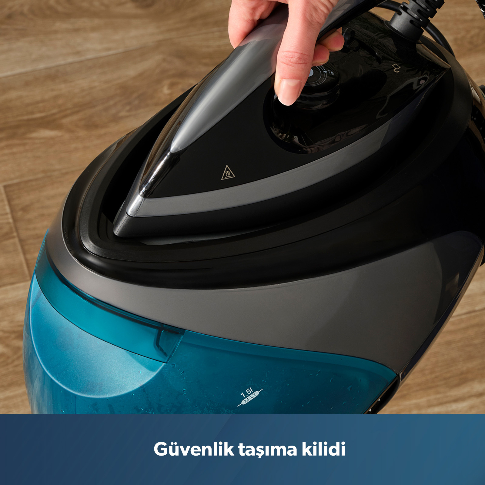Bir el, mavi su haznesine sahip siyah buharlı ütünün sapını tutuyor.