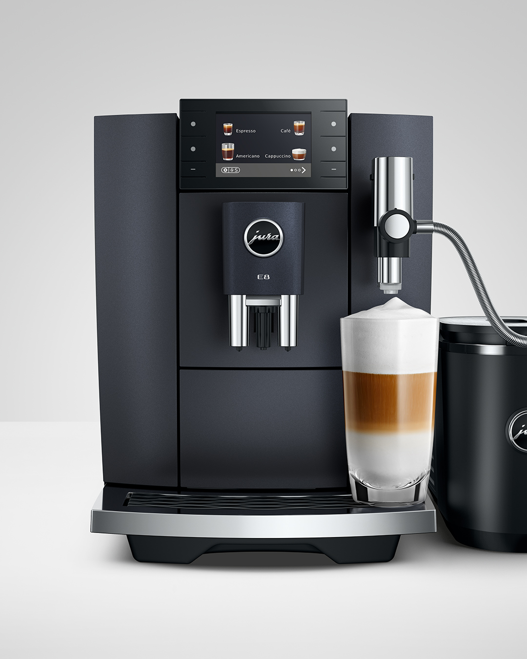 Egy fekete automata kávéfőző latte macchiato pohárral.