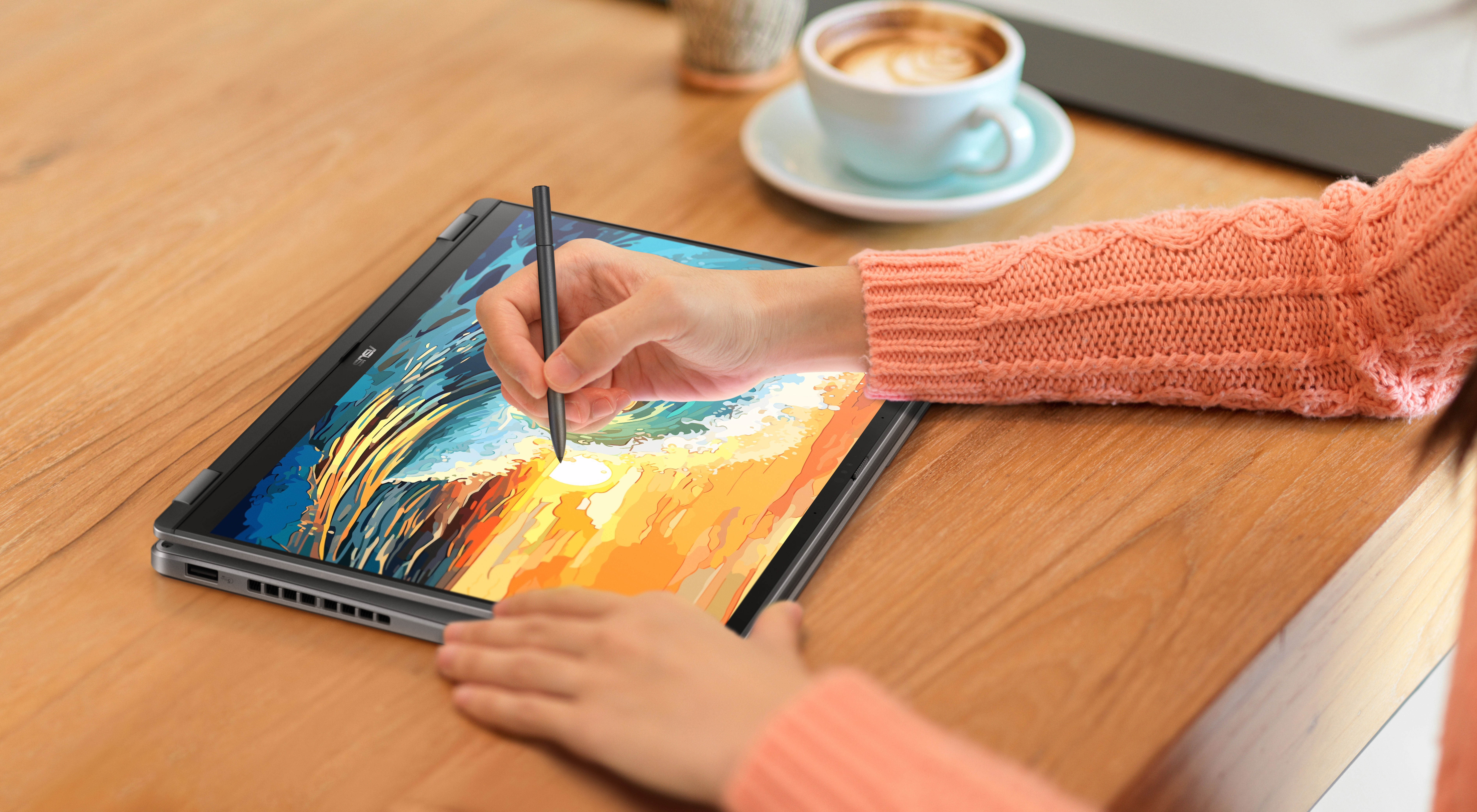 Eine Hand benutzt einen Stift, um auf einem Laptop zu zeichnen, mit Kaffee im Hintergrund.