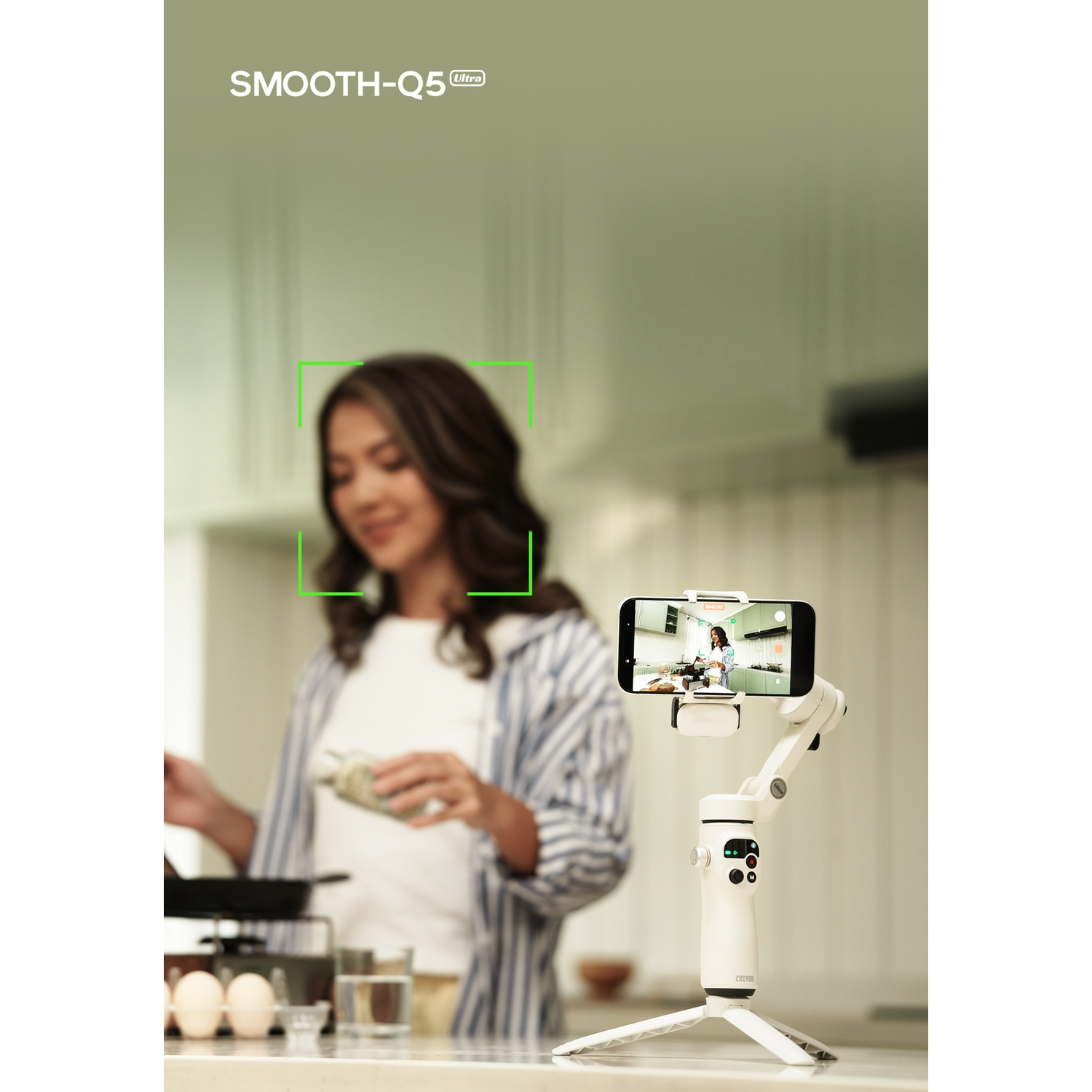 Une femme dans une cuisine se filme avec un cardan et un téléphone. Des œufs sont sur le comptoir.
