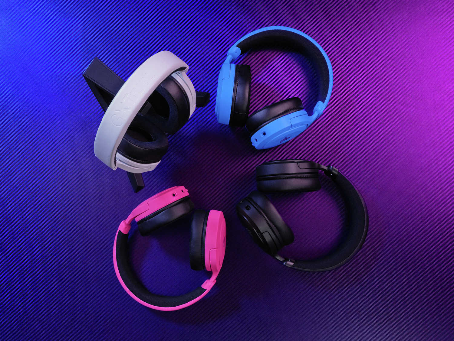 Cuatro pares de auriculares: blancos, azules, rosas y negros, sobre un fondo texturizado morado y azul.