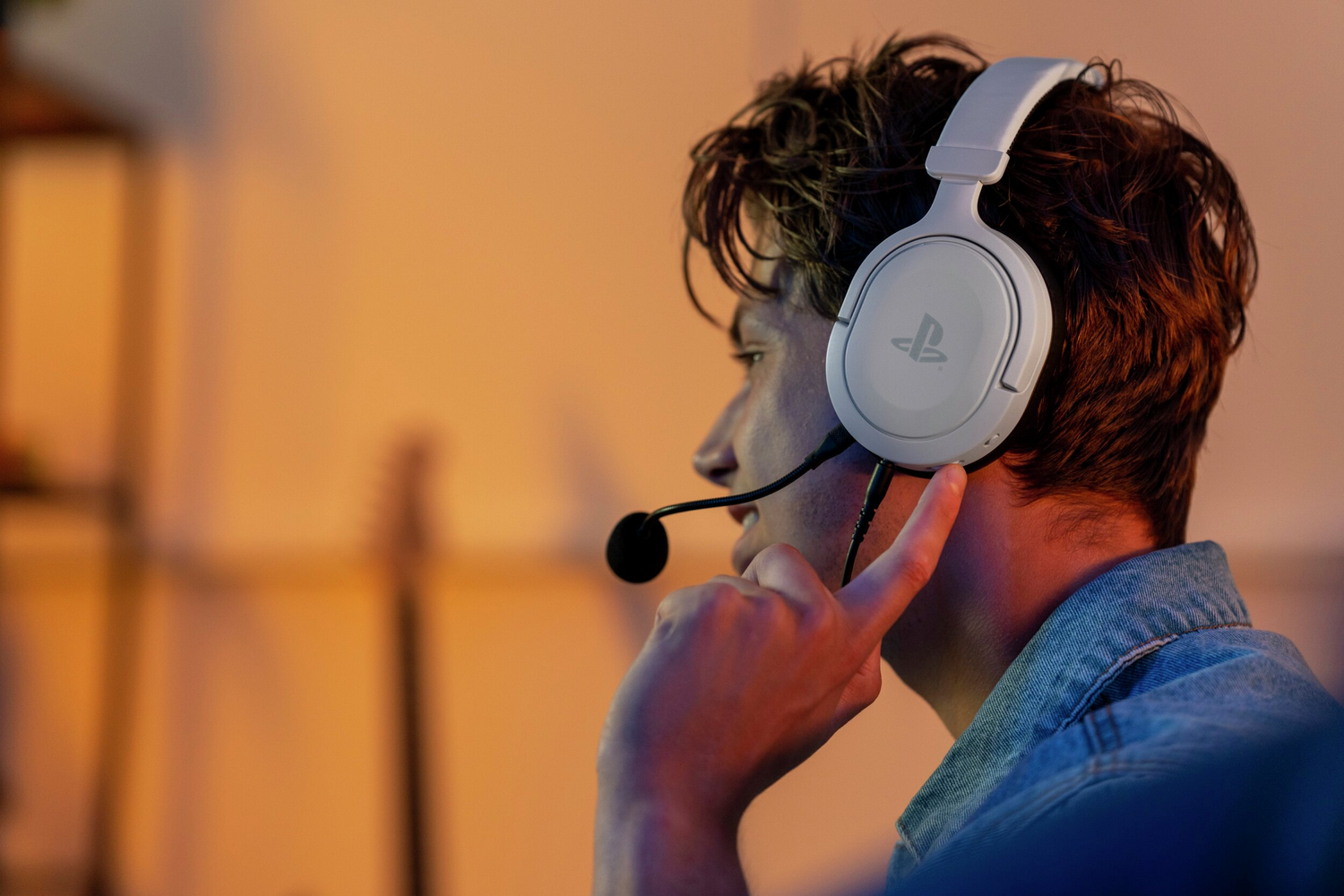 Un hombre con auriculares blancos y micrófono, mirando al fondo.
