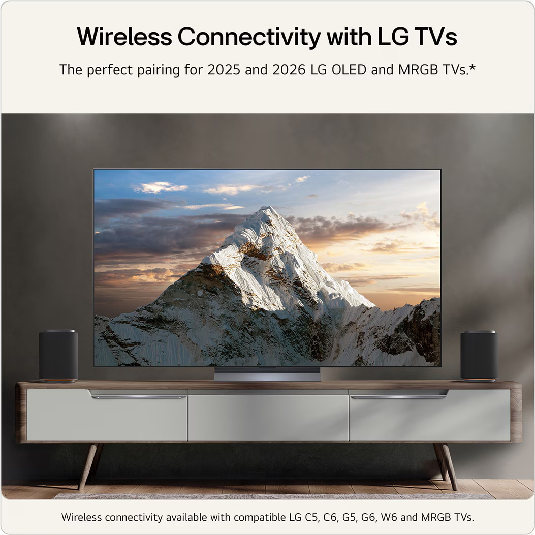 Une TV LG affiche une scène de montagne, flanquée d'enceintes sur un meuble TV.