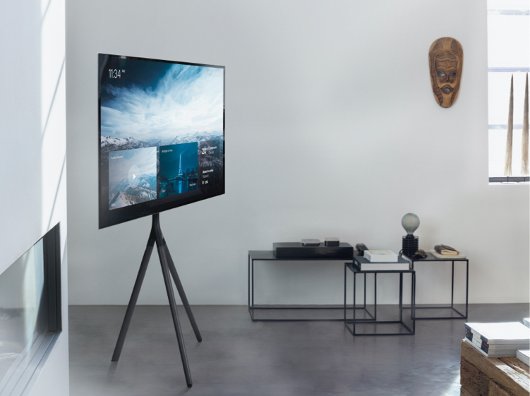 Un televisor moderno sobre un trípode en una sala minimalista.