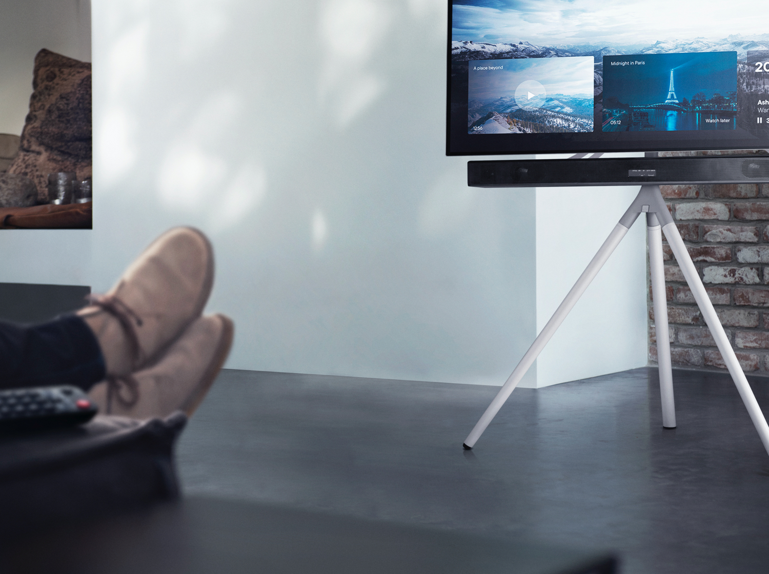 Una persona se relaja en casa, viendo películas en un televisor sobre un trípode.