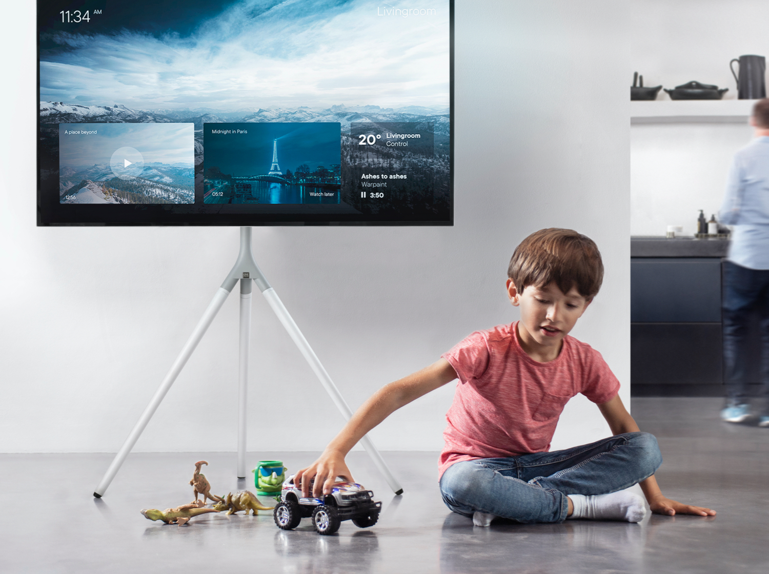 Un niño juega con coches de juguete y dinosaurios frente a un televisor inteligente.