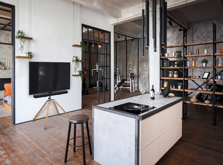 Moderna sala de estar tipo loft con cocina, TV, equipo de gimnasio y estantes.