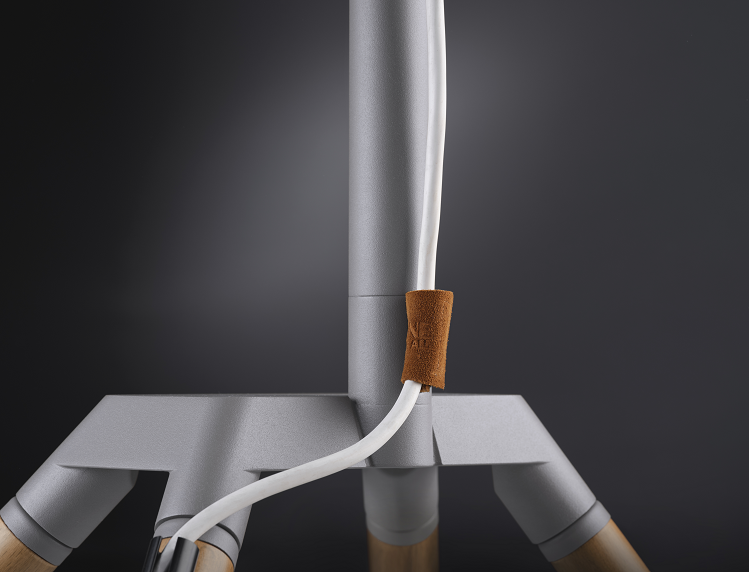 Base de lámpara gris con cable blanco sujeto por correa de cuero marrón.