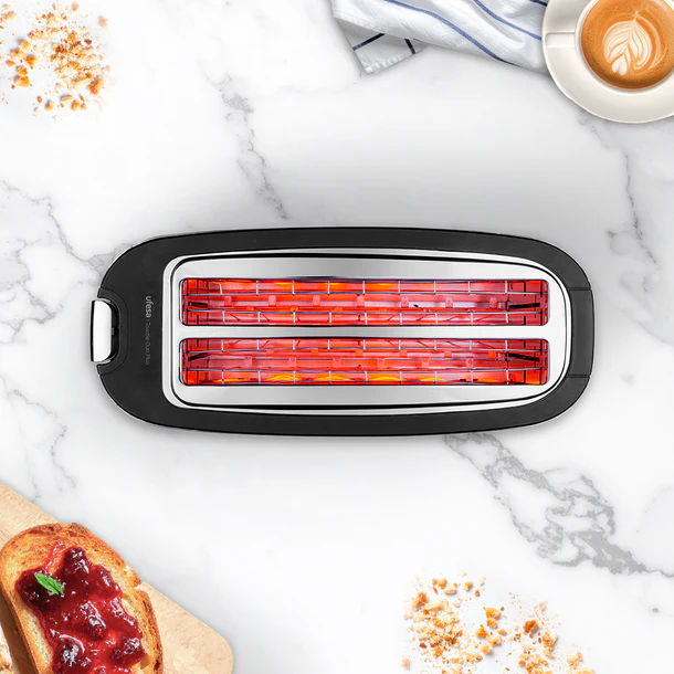 Una tostadora de dos ranuras con elementos calefactores incandescentes, junto a tostadas con mermelada.
