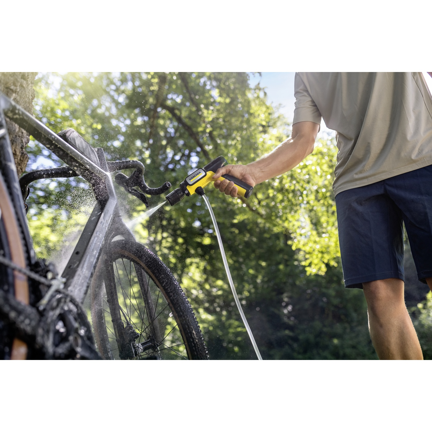 Persona lava bicicletta con idropulitrice all'aperto.