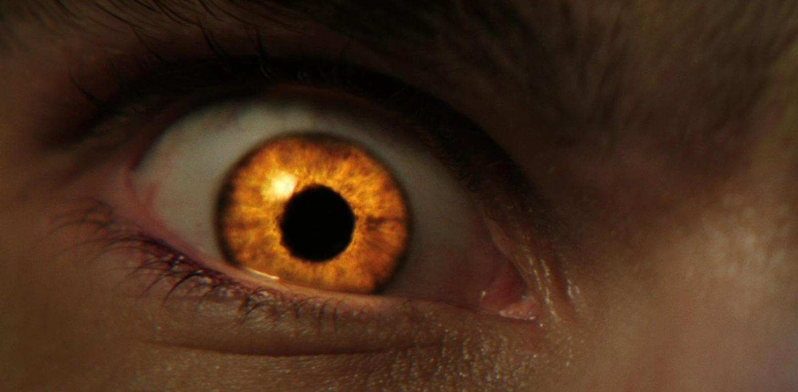 Nahaufnahme eines menschlichen Auges mit orangefarbener Iris und schwarzer Pupille.
