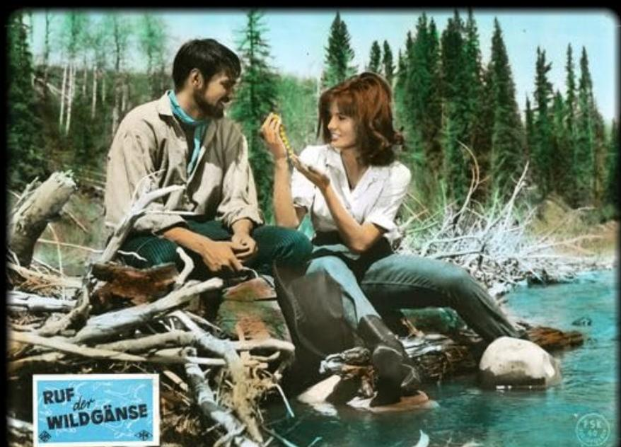 Ein Mann und eine Frau sitzen an einem Fluss und betrachten eine Kette.