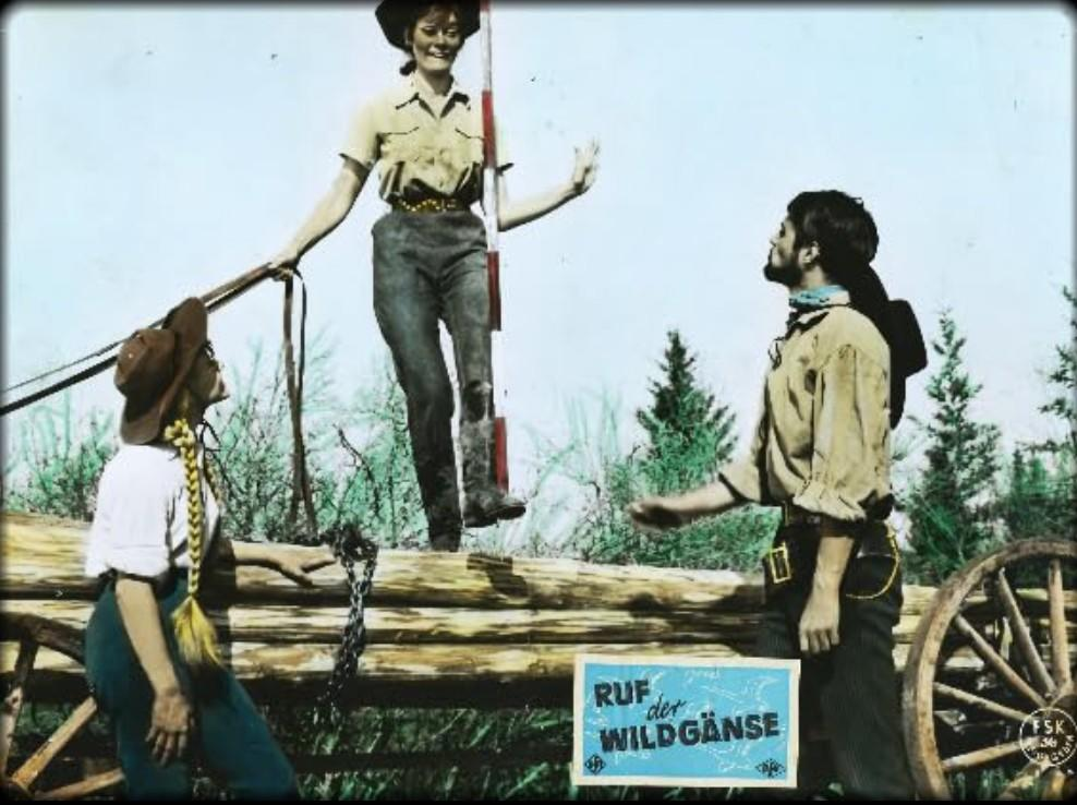 Drei Cowboys auf einem Holzstamm mit einem Wagenrad und einem Schild.