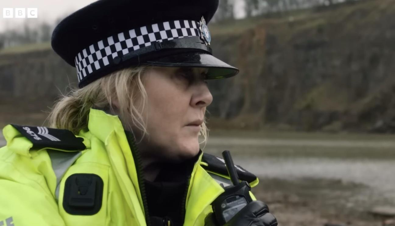 Eine Polizistin in Uniform mit gelber Jacke und Funkgerät.