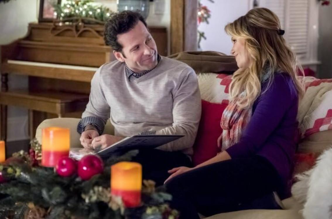 Ein Mann und eine Frau sitzen auf einem Sofa, mit Weihnachtsdekorationen im Vordergrund.