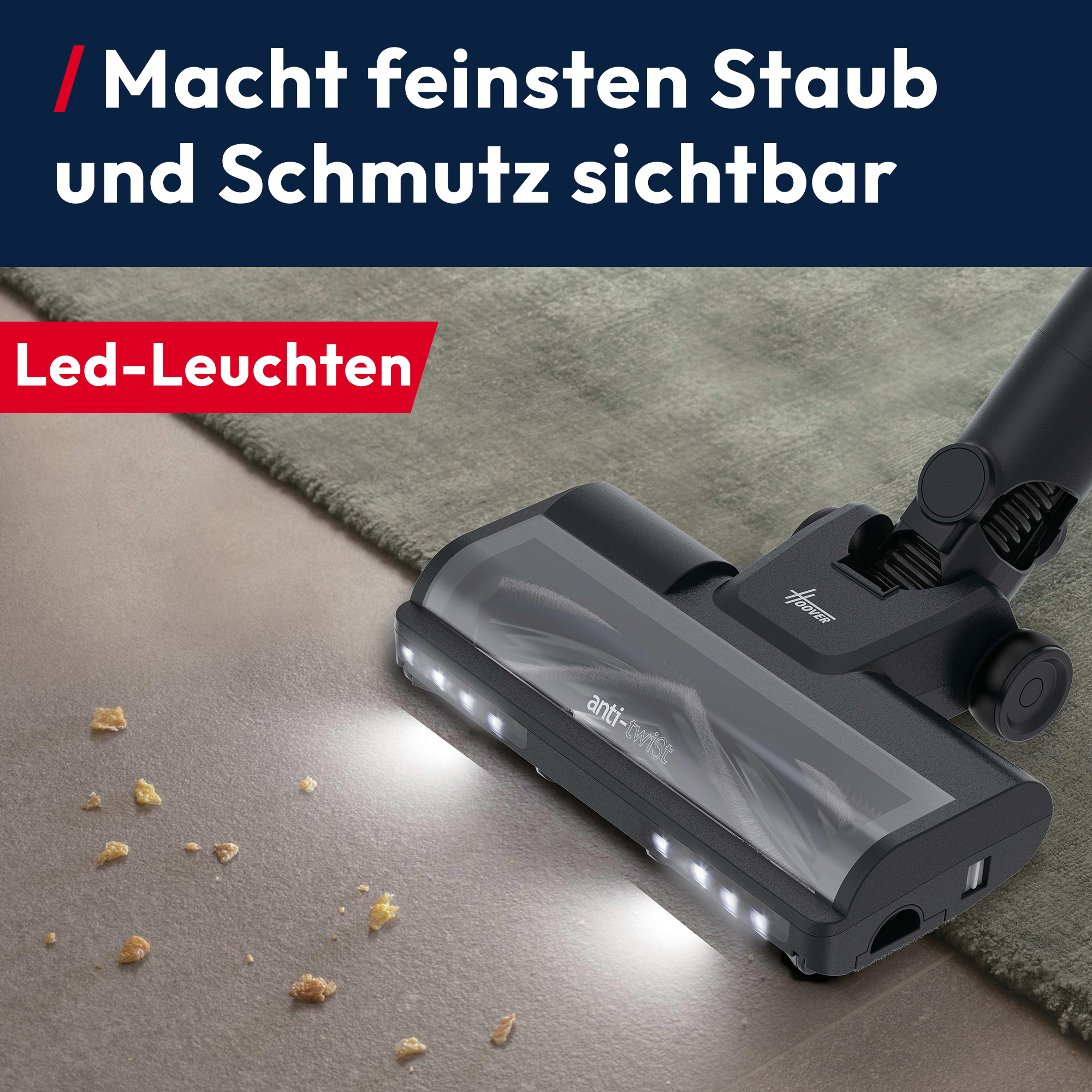 Dunkles Staubsaugerteil mit LEDs leuchtet Krümel auf grauem Boden aus.